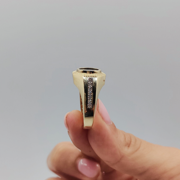 Un anillo de sello redondo con azabache y circonitas en los costados, elaborado en oro de 18 quilates, es una joya elegante y sofisticada