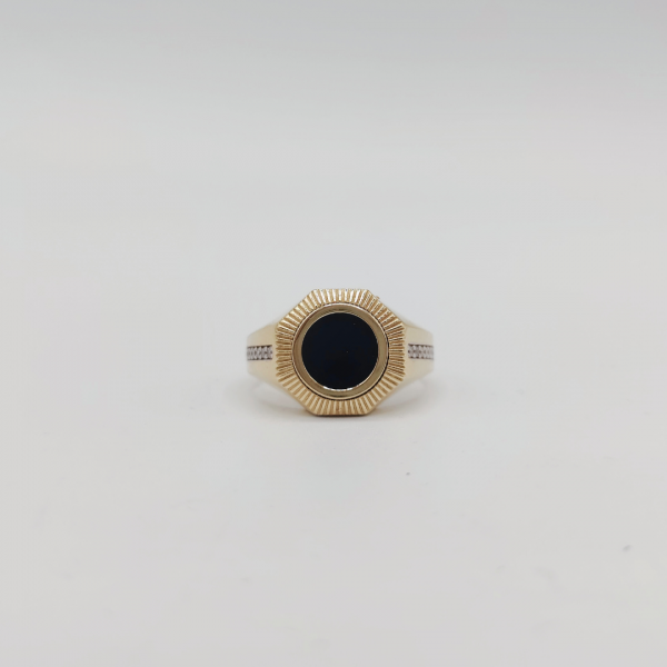 Un anillo de sello redondo con azabache y circonitas en los costados, elaborado en oro de 18 quilates, es una joya elegante y sofisticada