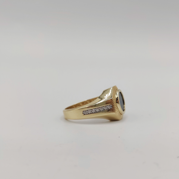 Un anillo de sello redondo con azabache y circonitas en los costados, elaborado en oro de 18 quilates, es una joya elegante y sofisticada