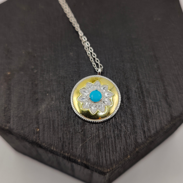 Collar de plata con colgante tipo medalla en color dorado con flor de circonitas y en el centro una piedra azul