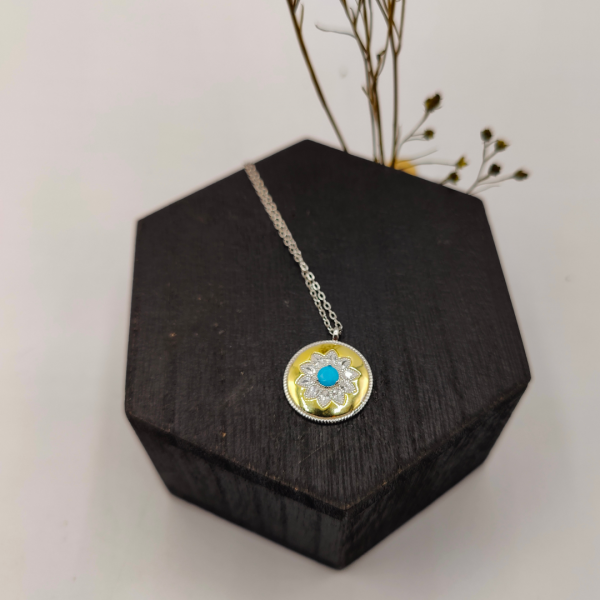 Collar de plata con colgante tipo medalla en color dorado con flor de circonitas y en el centro una piedra azul