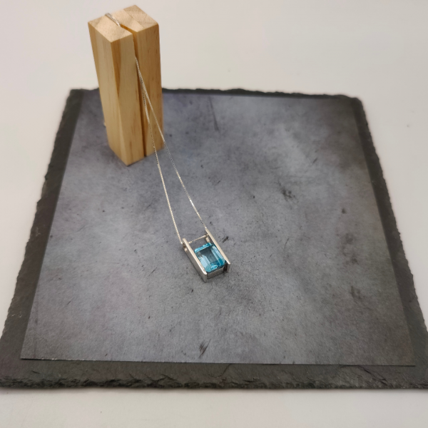 Colgante de plata con una piedra agua marina suspendida en el medio