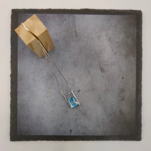 Colgante de plata con una piedra agua marina suspendida en el medio