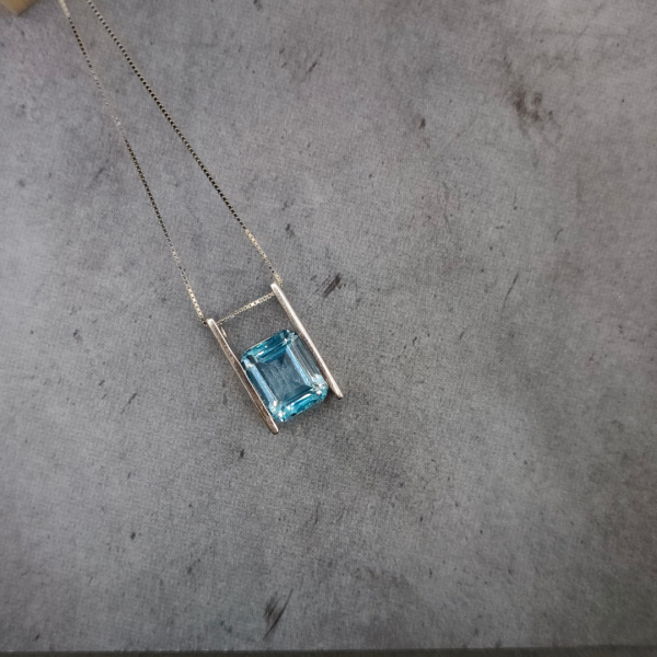 Colgante de plata con una piedra agua marina suspendida en el medio