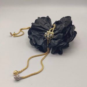 cadena estilo corbatín con eslabones tipo serpiente, cierre corazón con circonitas y el final de la cadena tiene dos borlas una de ellas lleva de circonitas
