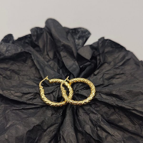 Este pendiente de aro de 2 cm de diámetro y 3 mm de ancho presenta una textura elegante que le da un toque sofisticado y moderno. Fabricado en oro de 18K