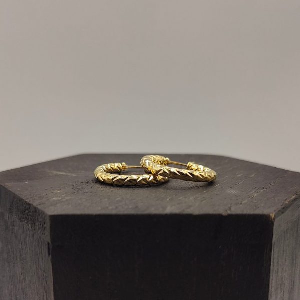 Este pendiente de aro de 2 cm de diámetro y 3 mm de ancho presenta una textura elegante que le da un toque sofisticado y moderno. Fabricado en oro de 18K